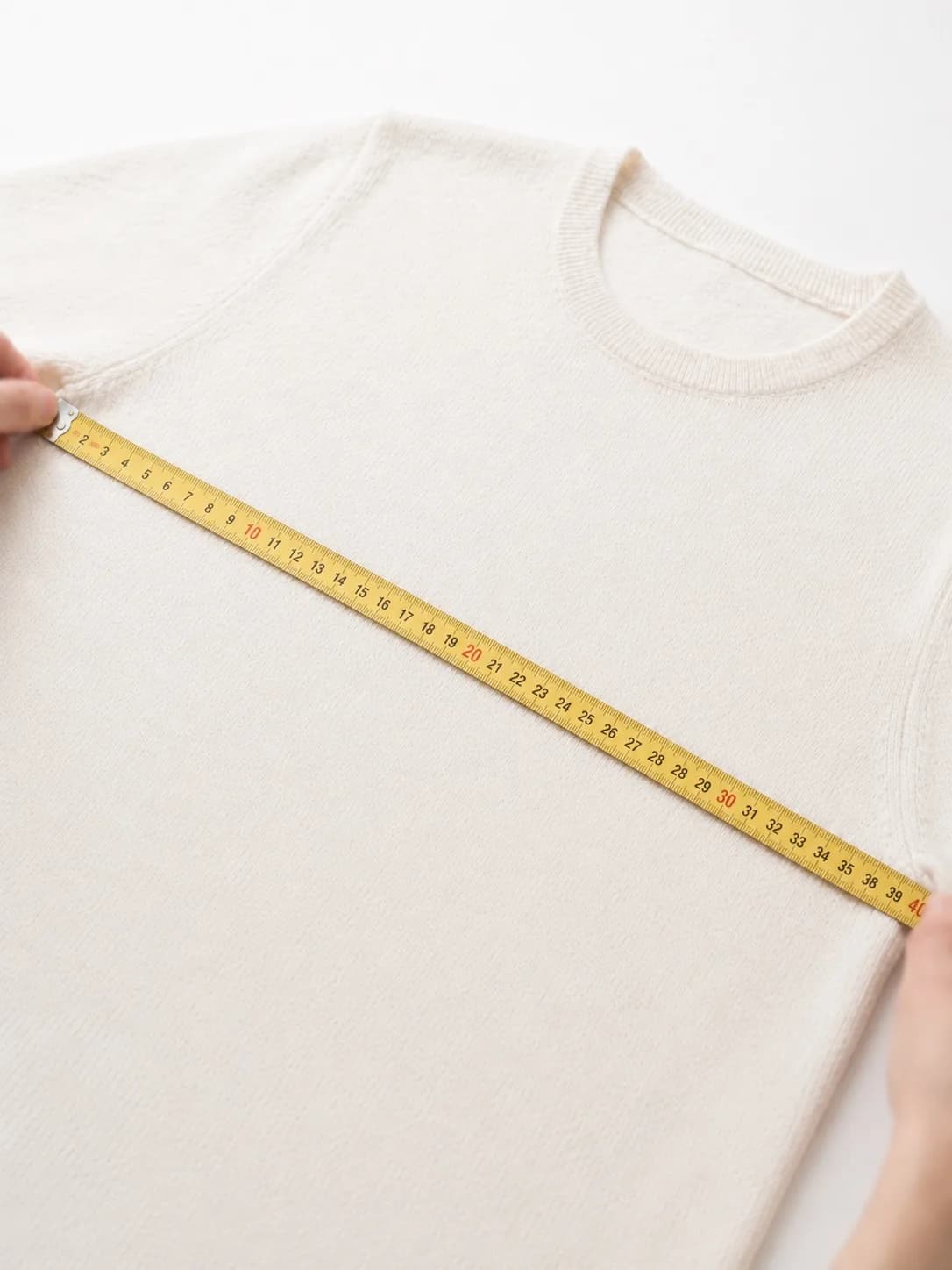 Measuring a white knitwear garment with a tape measure